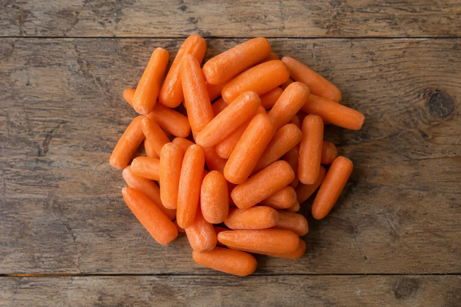Pile of baby carrots on a wooden board with calories and nutrition facts