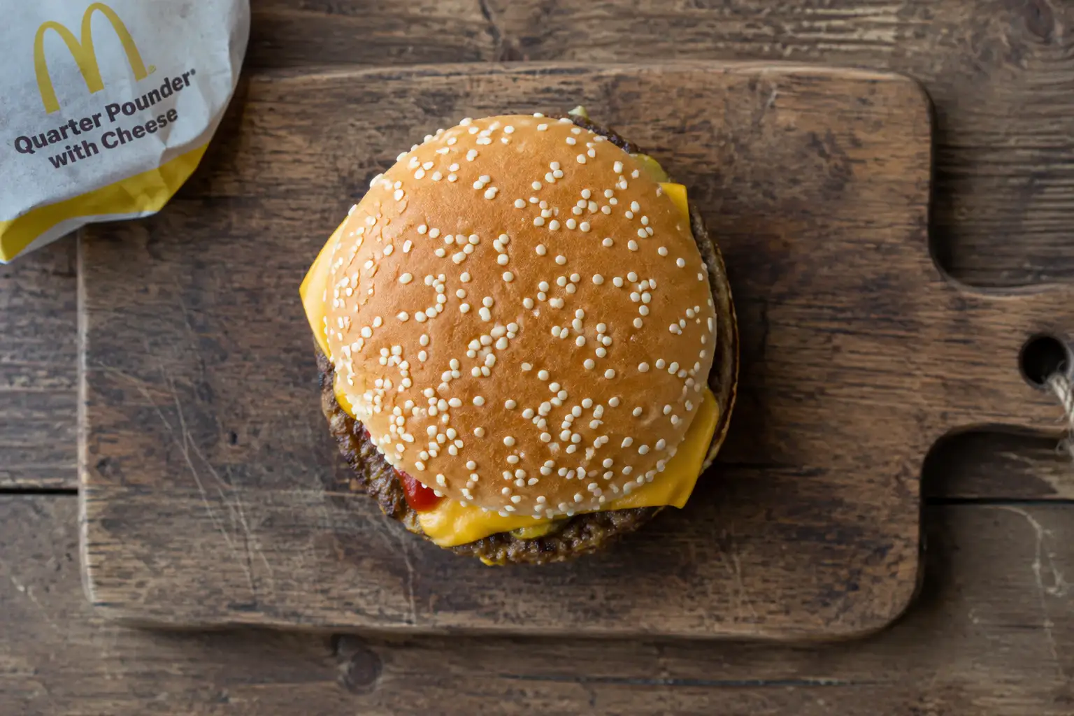Overhead view of a McDonald's Quarter Pounder with Cheese burger on a wooden board, showing Quarter Pounder with Cheese calories and nutrition facts