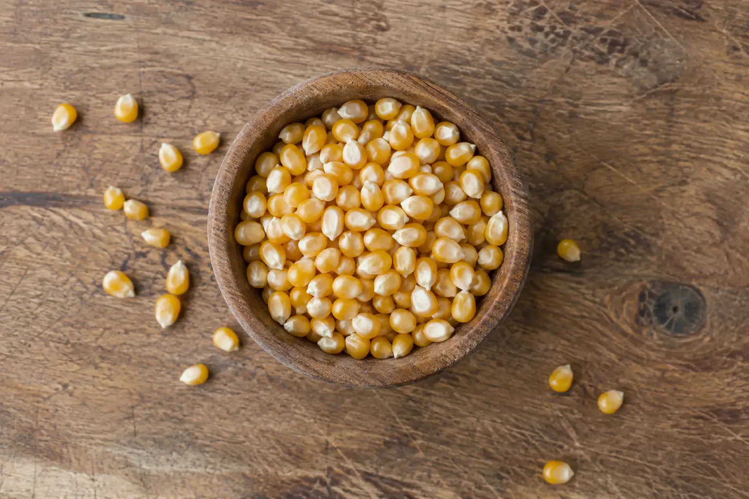 Wooden bowl of dry unpopped popcorn kernels with calories and nutrition facts