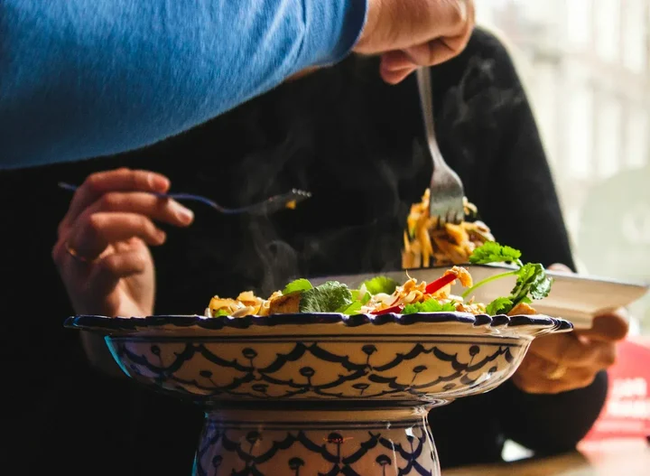 Person eating a healthy meal at a restaurant with fresh ingredients