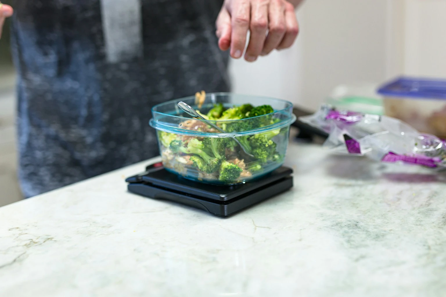 Meal prep containers on a clean kitchen table representing portion control and macro tracking for weight loss