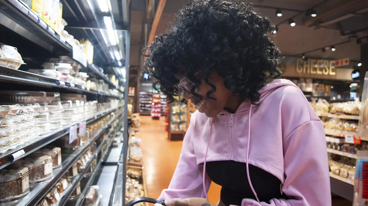 A young woman shopping in a grocery store aisle, checking products she logs most often