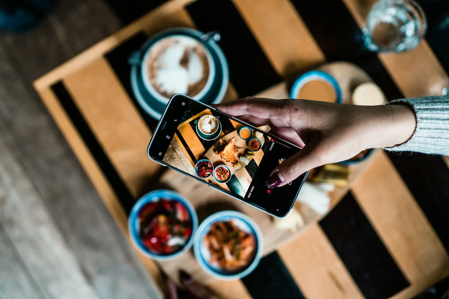 Person photographing their meal with a phone while running two tracking apps in parallel