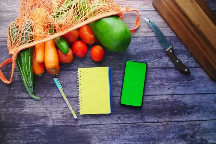 Liste de courses et légumes frais sur une table, illustrant la planification automatisée des repas