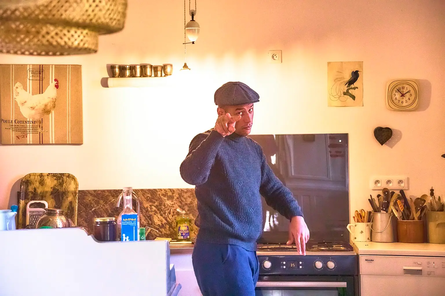 Man in flat cap talking on the phone in his kitchen